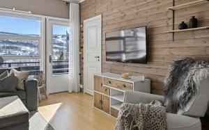 a living room with a television on a wooden wall at Geilo sentrum for 4 personer in Geilo