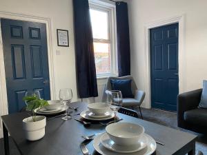 un comedor con una mesa con platos y copas de vino en Overhill - Spacious 2 bed ground floor flat close to Newcastle, en Gateshead