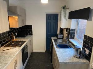 cocina con fregadero y puerta azul en Overhill - Spacious 2 bed ground floor flat close to Newcastle, en Gateshead
