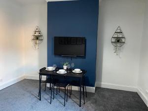 una mesa negra con sillas y una TV en una pared azul en Overhill - Spacious 2 bed ground floor flat close to Newcastle, en Gateshead