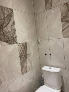 Nice apartment في Pʼonichala: حمام به مرحاض وجدار من البلاط