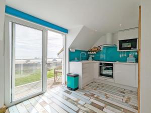 cocina con electrodomésticos azules y ventana grande en Sea Esta en Selsey