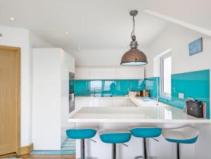 eine Küche mit blauen und weißen Arbeitsflächen und Stühlen in der Unterkunft Seaside in Selsey