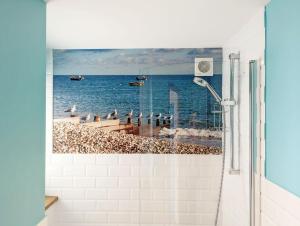 a bathroom with a shower with a picture of the ocean at Seaside in Selsey +32 photos