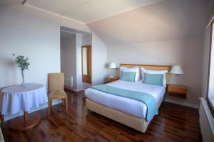 a bedroom with a large bed and a table at Gran Hotel Vicente Costanera in Puerto Montt