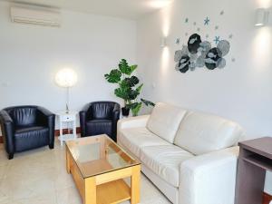 uma sala de estar com um sofá branco e duas cadeiras pretas em Apartment Carica em Slatine