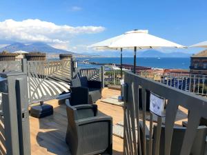 einen Balkon mit Stühlen, einem Sonnenschirm und dem Meer in der Unterkunft B&B Musica e Mare in Neapel