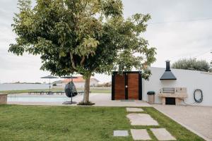 un árbol y un banco al lado de un edificio en Sete Azenhas, en Esposende