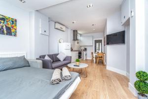 ein Schlafzimmer mit einem Bett, einem Sofa und einem Tisch in der Unterkunft Modern Apartment in East London in London
