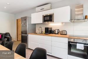 a kitchen with white cabinets and black appliances at Dandelion Apartments Lāčplēša in Rīga