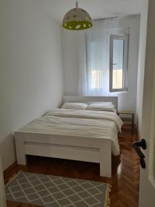 a white bed in a room with a window at Serenity City Centre in Podgorica