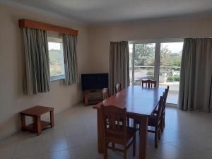 Un comedor con mesa y sillas y un televisor. en Vila Marachique lt 6 107, en Alvor