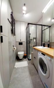 a bathroom with a toilet and a washing machine at NeoApartments Lotnicza in Wrocław
