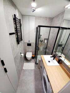 a bathroom with a toilet and a sink and a washing machine at NeoApartments Lotnicza in Wrocław