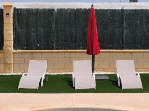 three white chairs and an umbrella in a yard at Belvilla by OYO Villa Valerya in Ibáñez