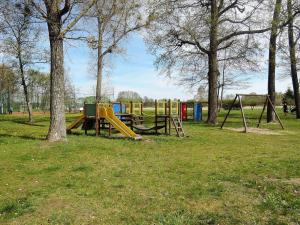 un parque con un parque infantil con 2 columpios y árboles en Holiday flat, Stepnica, en Stepnica