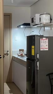 a kitchen with a refrigerator and a microwave on a shelf at OK kada Inn Quezon City in Manila