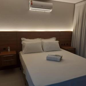 a bedroom with a white bed with a air conditioner at Pousada Bienenwabe Suítes in São Pedro de Alcântara