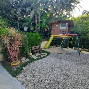 a playground with a slide and a bench and a house at Pousada Bienenwabe Suítes in São Pedro de Alcântara