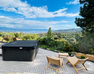 d'une terrasse avec des chaises et un grand tombereau noir. dans l'établissement CHAMBRE DELUXE 2 vue Mer Jacuzzi, à Ajaccio