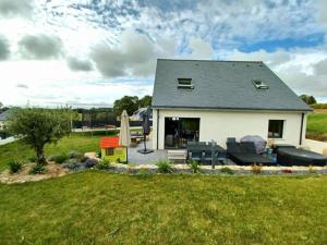 una pequeña casa blanca con un patio de césped en Maison Morbihan avec jacuzzi, en Landaul