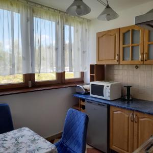 una cucina con forno a microonde e bancone con sedie di Mieszkanie z balkonem a Głuszyca Altre 11 foto
