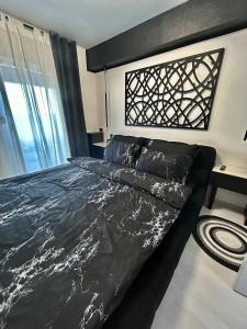 een slaapkamer met een bed met een zwart dekbed bij Sandev apartments Black&White in Štip