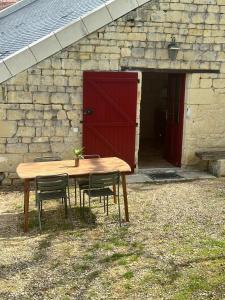 une table et des chaises en bois devant une grange dans l'établissement Gîte du château, à Thizay