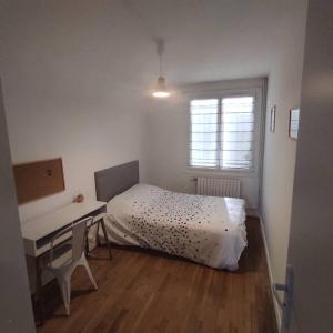 Schlafzimmer mit einem Bett, einem Schreibtisch und einem Fenster in der Unterkunft Maison 6 chambres avec jardin à Angers in Angers
