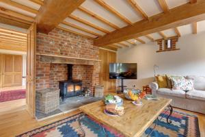 a living room with a brick fireplace and a table at Williams Barn in West Beckham