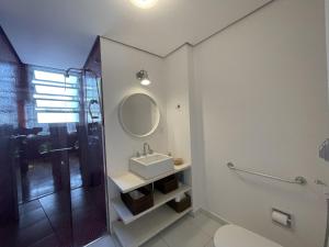 uma casa de banho com um lavatório e um chuveiro com um espelho. em Akile Parque Aclimacao em São Paulo