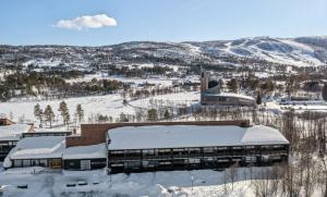 a building covered in snow next to a mountain at Geilo sentrum for 4 personer in Geilo