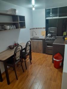 y cocina con mesa, sillas y fogones. en Karito's house, en Puno