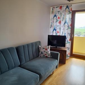 a living room with a blue couch and a television at Mieszkanie z balkonem in Głuszyca