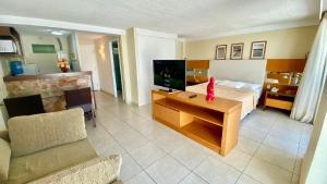 a hotel room with a bed and a tv and a couch at Varandas 108 Ponta Negra Praia - NBI - (Perto da Praia e Morro de Careca) in Natal
