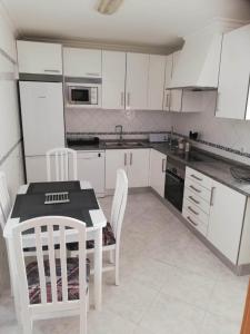 a kitchen with white cabinets and a table and chairs at Apartamento Saint Martin in Armação de Pêra