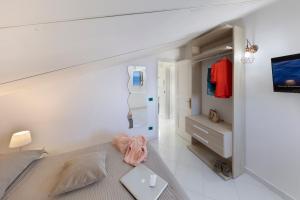ein weißes Schlafzimmer mit einem Bett und einem TV in der Unterkunft Relais del mare con terrazza fronte mare free parking in Massa Lubrense