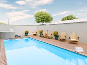 a swimming pool with chairs and a table at JetPark Hotel Rotorua in Rotorua