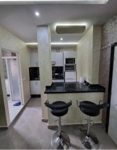 une cuisine avec un comptoir et deux tabourets de bar dans l'établissement Comforts apartments 1, à Fnideq