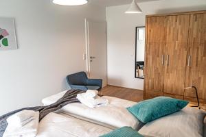 ein Schlafzimmer mit einem Bett und einem blauen Stuhl in der Unterkunft Top 5 Alpe Maritima - Traumhafte Ferienwohnung mit Seeblick und Bergkulisse am Ossiacher See in Annenheim