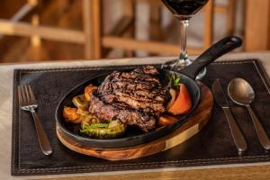 einen Teller Steak und Gemüse mit einem Glas Wein in der Unterkunft Pampa Lodge, Quincho & Caballos in Torres del Paine