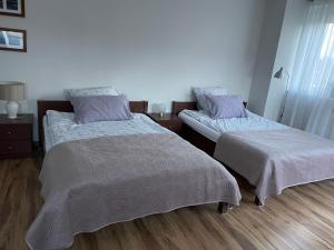 a bedroom with two beds and a wooden floor at Apartament Aga in Stegna