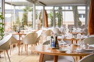 un ristorante con tavoli e sedie in legno e finestre di Holiday Inn Perpignan, an IHG Hotel a Perpignano
