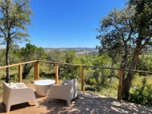 una terraza con sillas blancas y una bañera. en Nature Nest Aljezur, en Aljezur