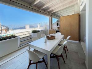 een witte tafel en stoelen in een kamer met een groot raam bij Luxury sea view home/4-min walk to beach in Marinella