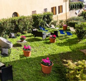 a yard with pots of flowers in the grass at Hotel Minerva in Siena