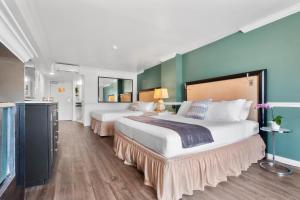 2 Betten in einem Hotelzimmer mit blauen Wänden in der Unterkunft Ascot Suites Morro Bay in Morro Bay