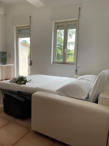 ein großes weißes Bett in einem Zimmer mit zwei Fenstern in der Unterkunft Just Relax in Le Casette