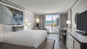 um quarto com uma cama e uma secretária com uma televisão em Loews Miami Beach Hotel em Miami Beach