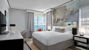 a bedroom with a bed and a desk and a television at Loews Miami Beach Hotel in Miami Beach